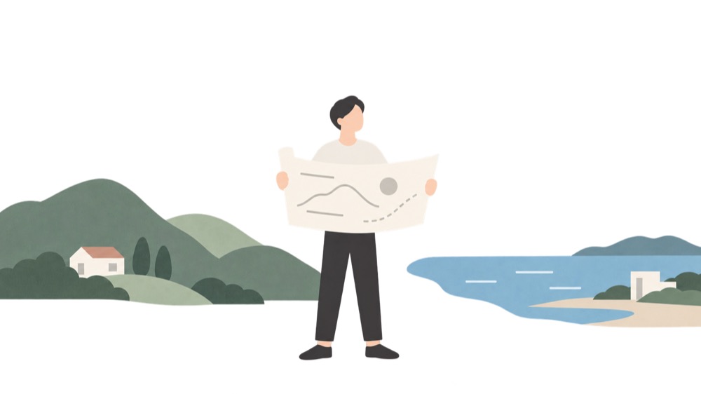 山と海のあいだに立ち、広げた図面を見ている人